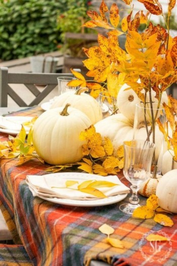 Fall table setting with pumpkins and leaves.