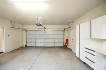 Empty garage with white cabinets and a door.