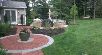 Brick patio with a green lawn and trees.